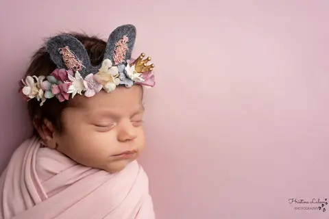 Новородено в розова повивка с венче от цветя, зайчешки ушички и златна коронка