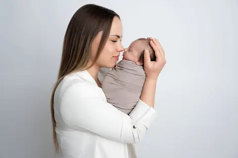 Мама в бяло сако нежно докосва с нос мъничкото носле на бебето